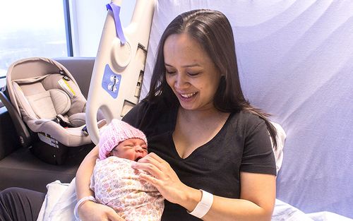 Emery Mendoza relaxes with her 3-day-old daughter, who wears a hat made by the knitting group at La Résidence Steger.